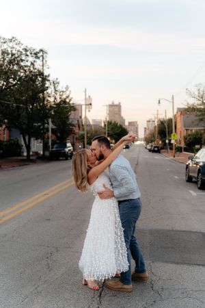 A romantic dance pose in the middle of a city street at dusk with urban buildings behind.