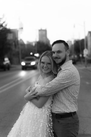 A joyful black and white portrait embrace with city lights twinkling in the background.