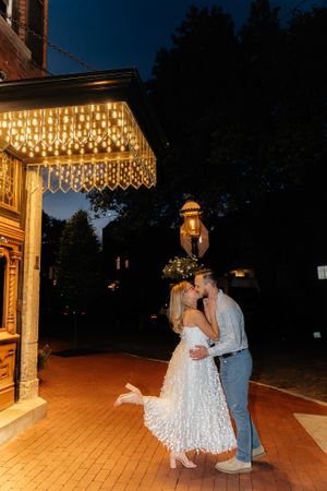 A romantic moment under twinkling lights on a wooden porch at night.