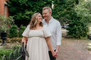 A couple shares an intimate moment while standing on a brick pathway.