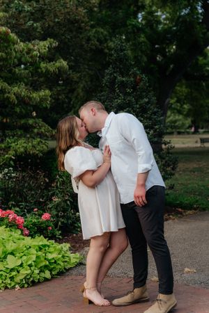 Sweet moment captured in a garden setting with blooming flowers and brick pathway.