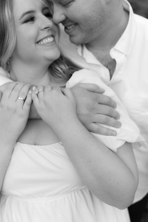 Black and white intimate portrait highlighting tender moment and engagement ring.