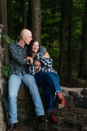 A candid moment of laughter shared while sitting on a stone wall surrounded by forest.