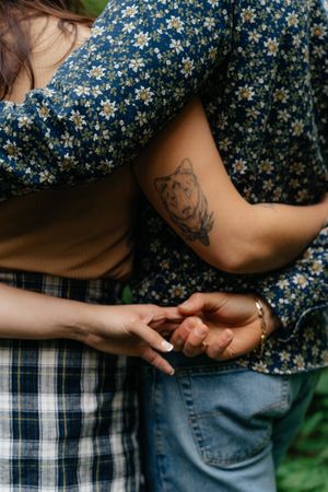 Close-up detail of hands touching with a wolf tattoo visible on one arm.
