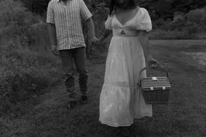 A black and white image of a couple walking with a picnic basket on a nature path.