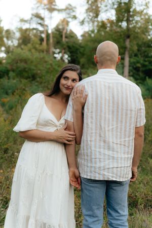 A couple shares an intimate moment together in a sunlit forest clearing.
