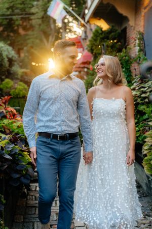 Couple shares joyful moment in lush garden setting with string lights and flags.