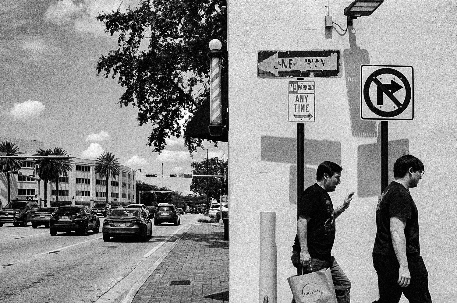 Black and white urban street scene with buildings and traffic signs.