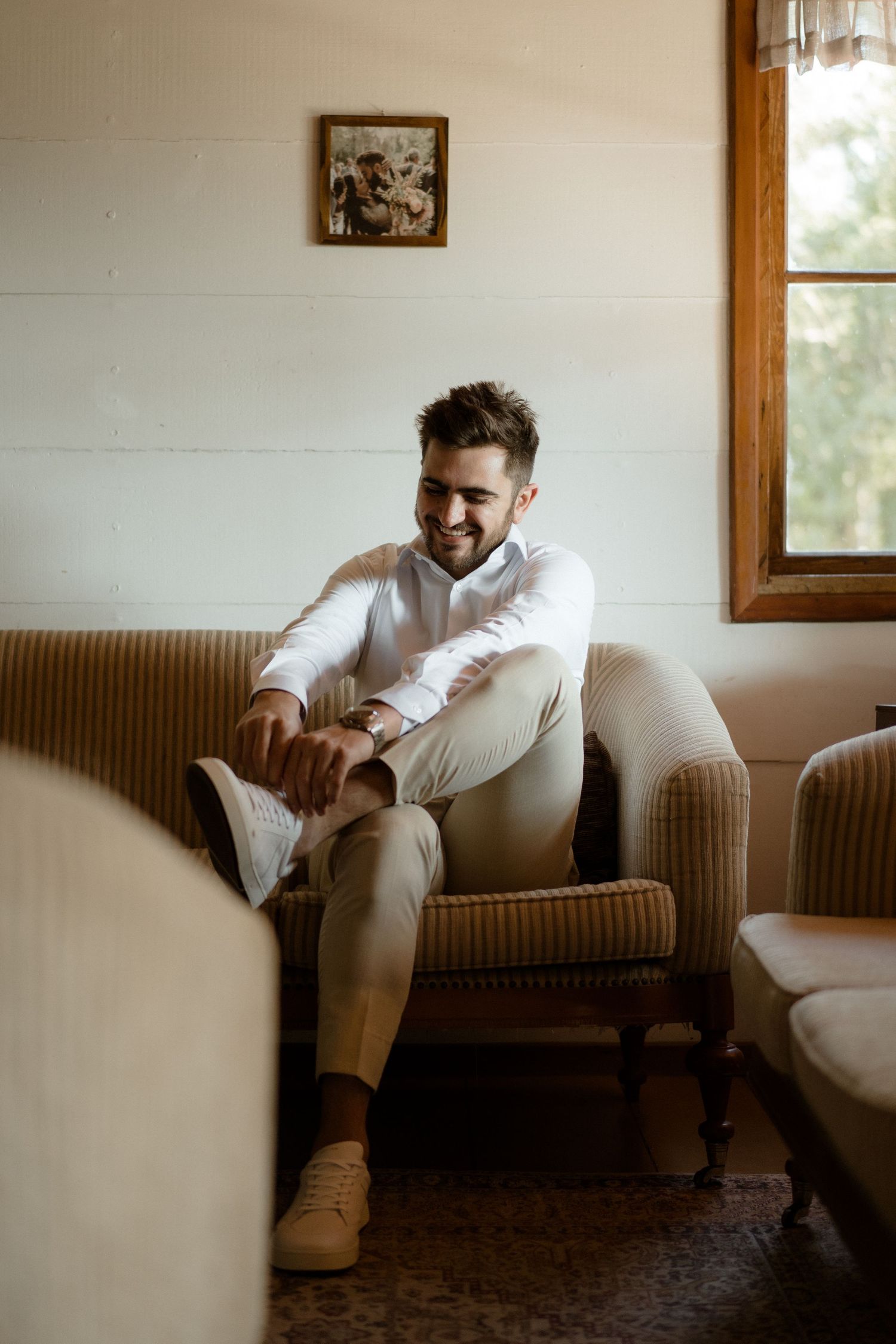Person relaxing in a striped armchair wearing all white casual attire.