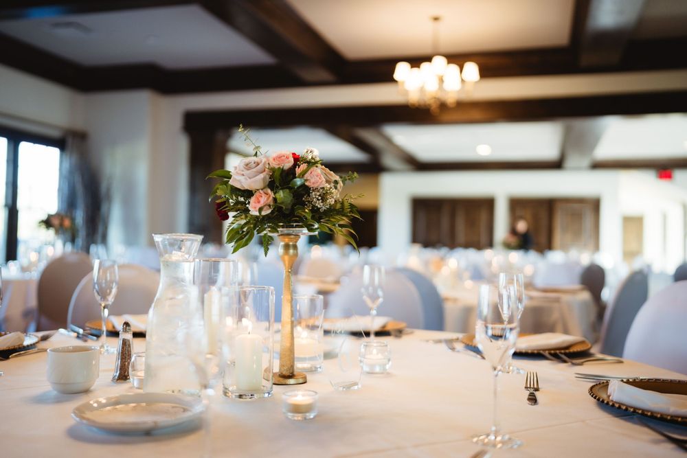 Wedding table setting with floral centerpiece, crystal glasses and white linens.