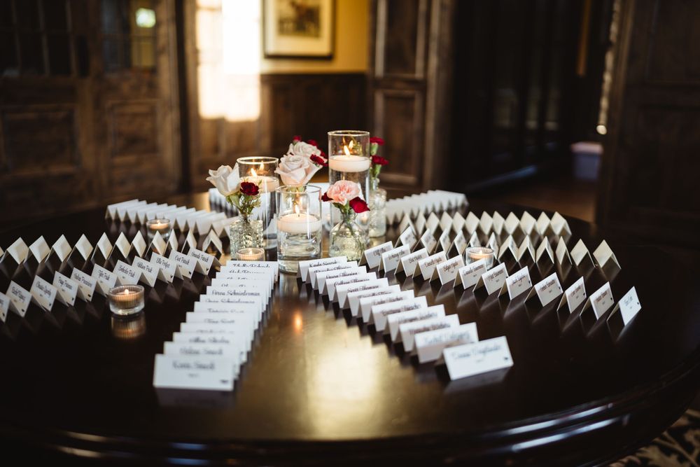 Wedding place cards arranged in a geometric pattern on dark wooden table.