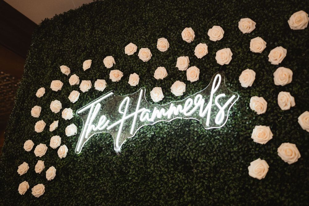 Neon 'La Havens' sign mounted on green hedge wall with white floral accents.