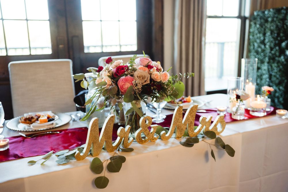 Head table with 'Mr & Mrs' sign, pink florals and eucalyptus garland decoration.
