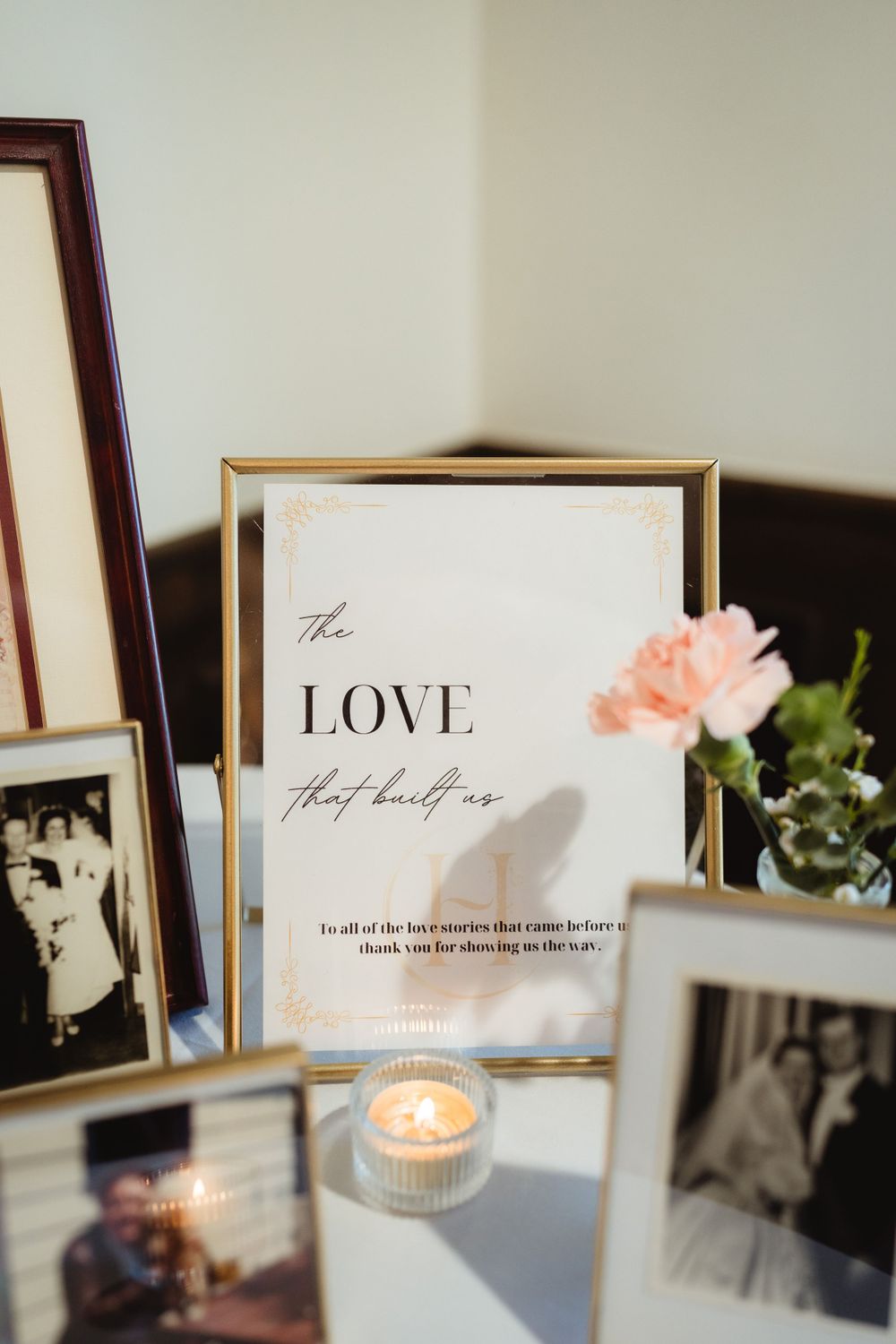 Framed 'LOVE' typography print with pink flowers and vintage photos on display.
