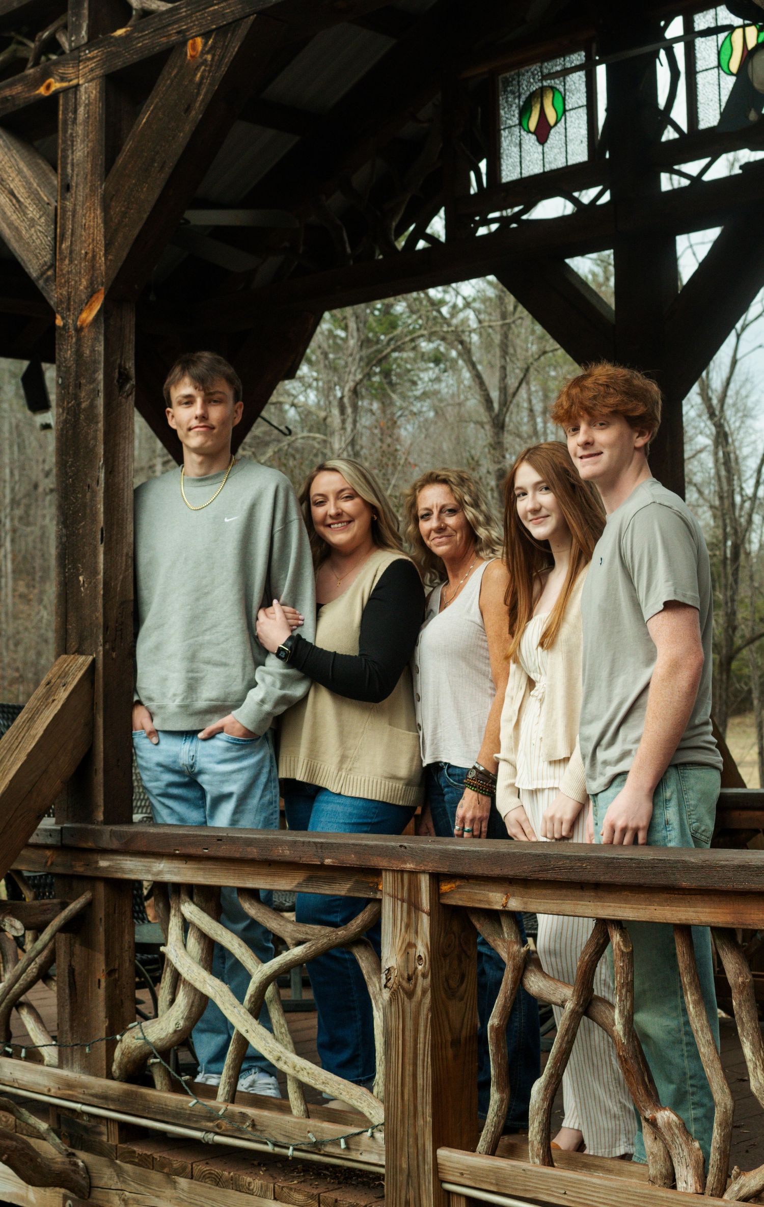 Group posing together on a rustic wooden deck surrounded by trees.