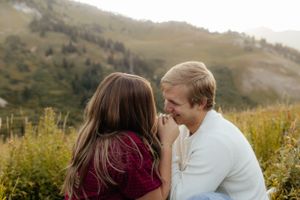 Couple sharing a tender moment in a lush green mountain field.