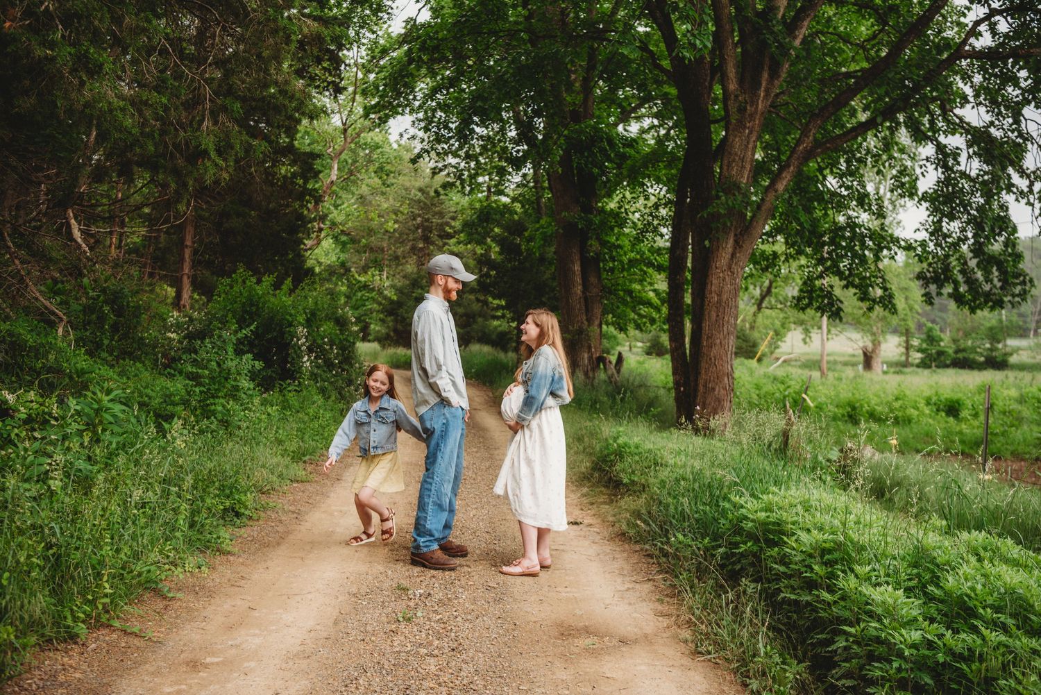 Family enjoying a casual stroll together on a peaceful dirt road surrounded by trees.