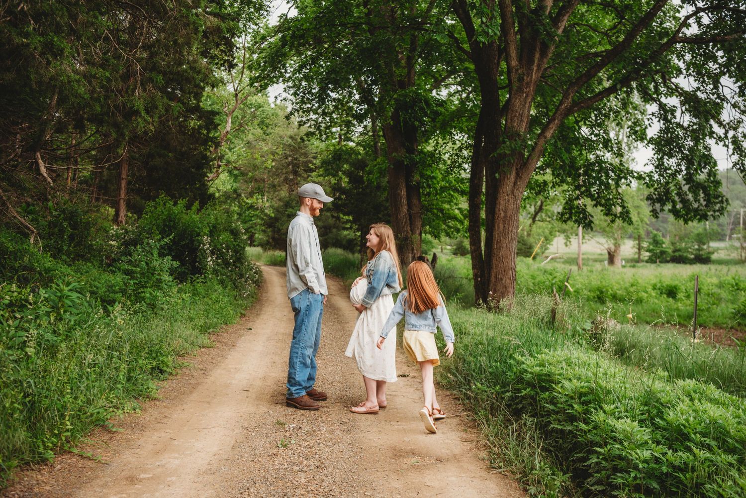 Scenic family photo on a tree-lined dirt path in a lush green setting.