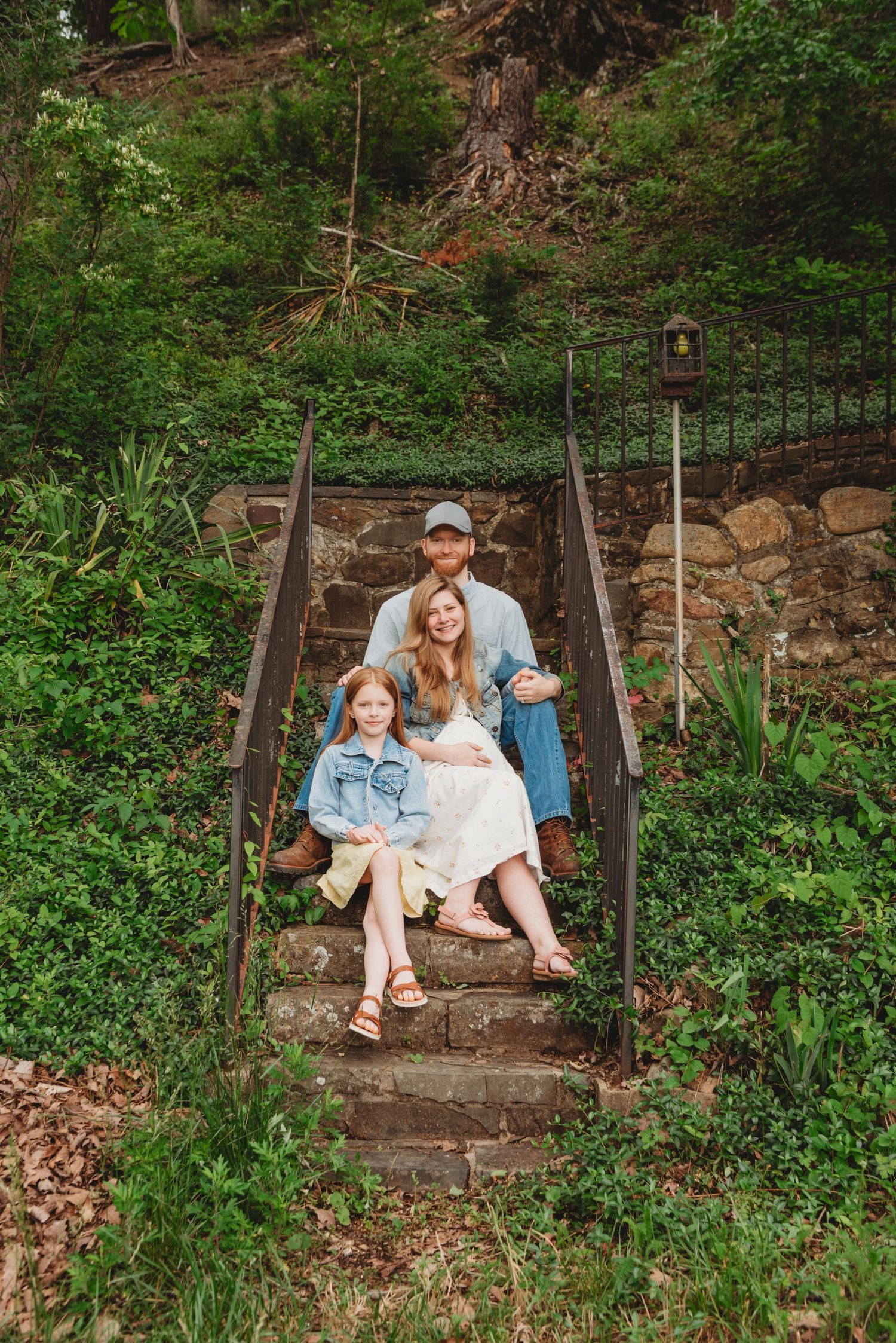 Family portrait taken on rustic stone steps in a wooded garden setting.