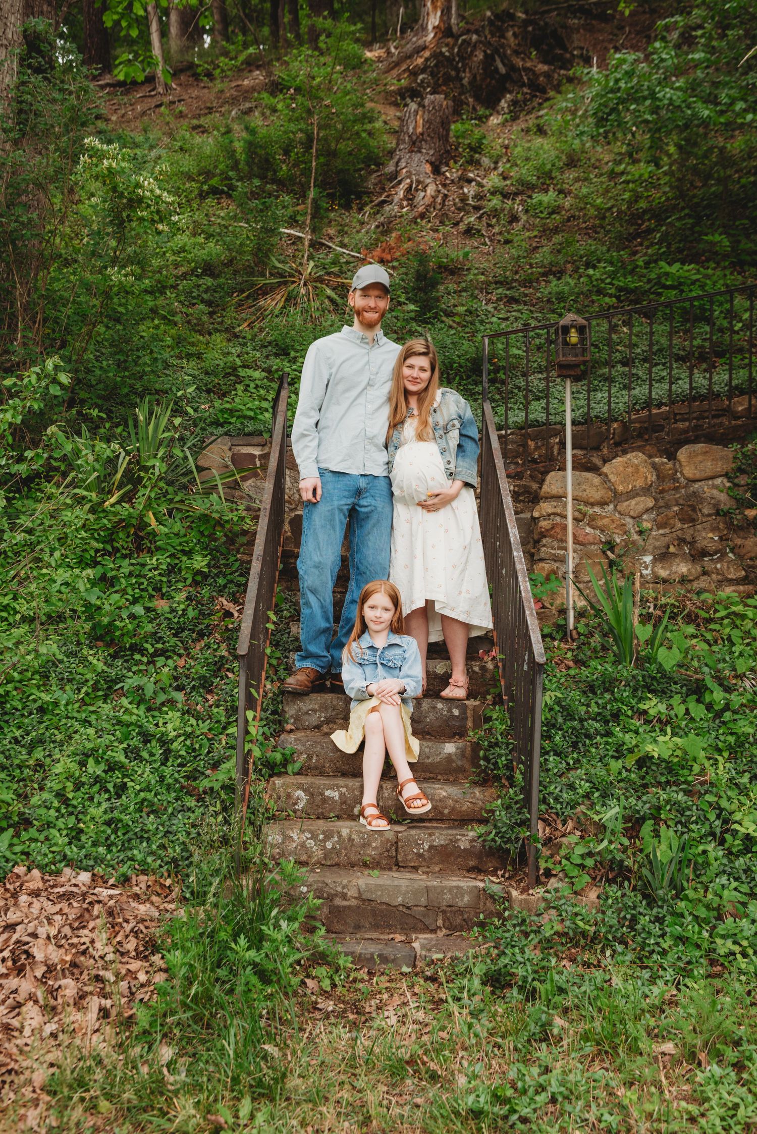 Family posing together on stone steps in a lush garden landscape.