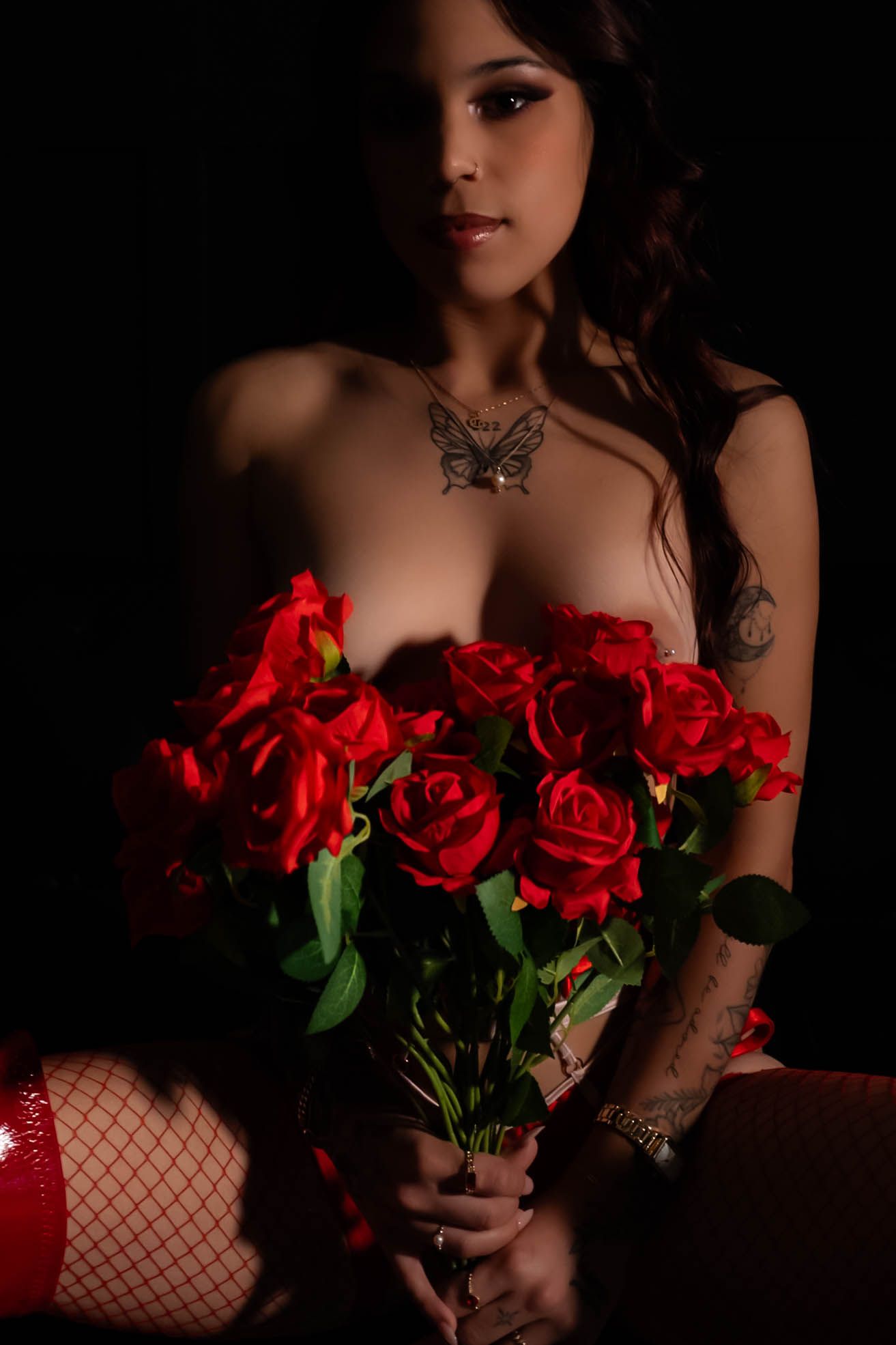 Dramatic portrait with red roses against dark background.