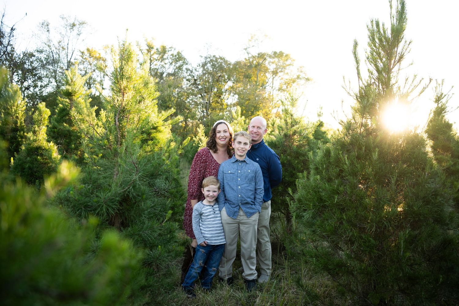 Family gathered among evergreen trees during sunset for holiday photos in Columbia, TN.