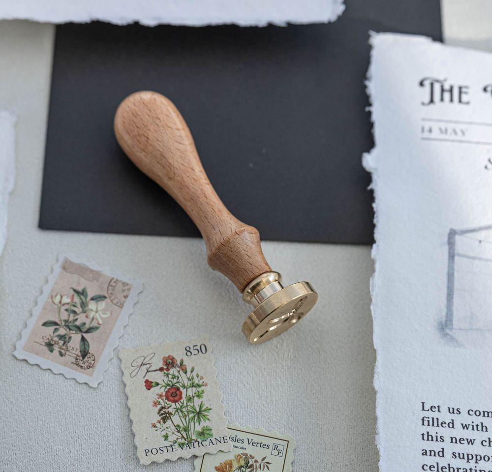 Vintage wooden wax seal stamp with decorative postage stamps and document on light background.