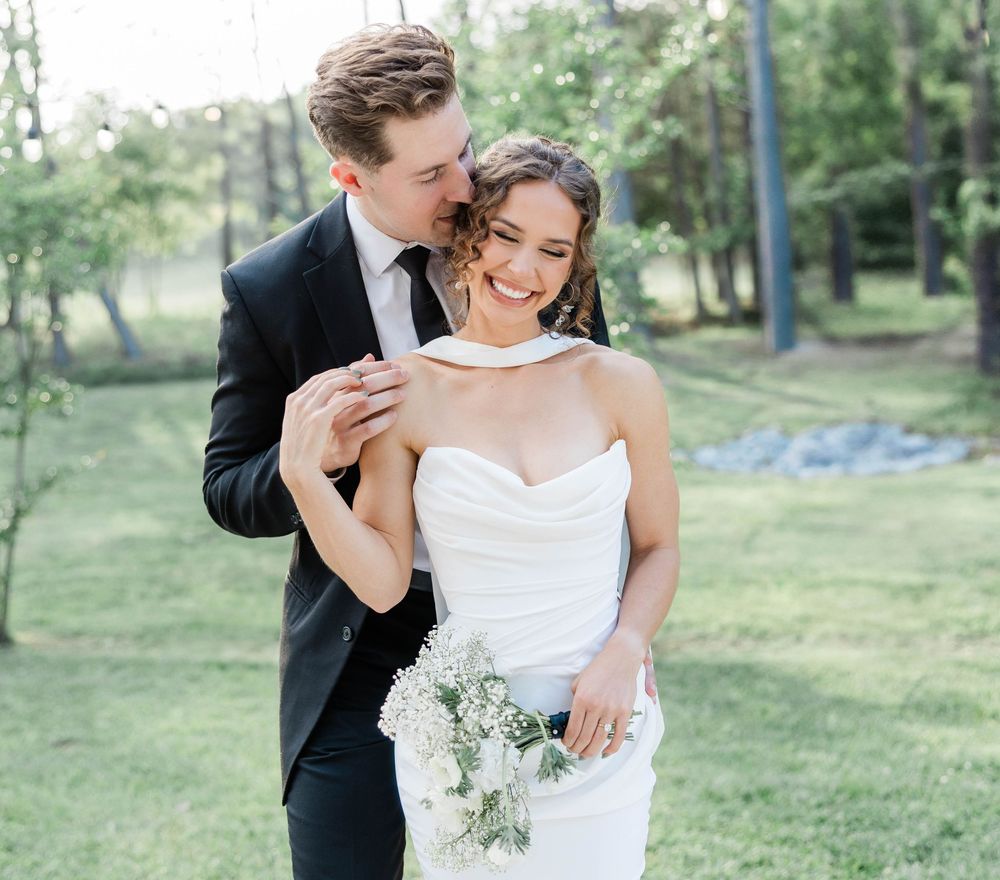 Romantic wedding portrait with couple embracing in a sunlit garden setting.