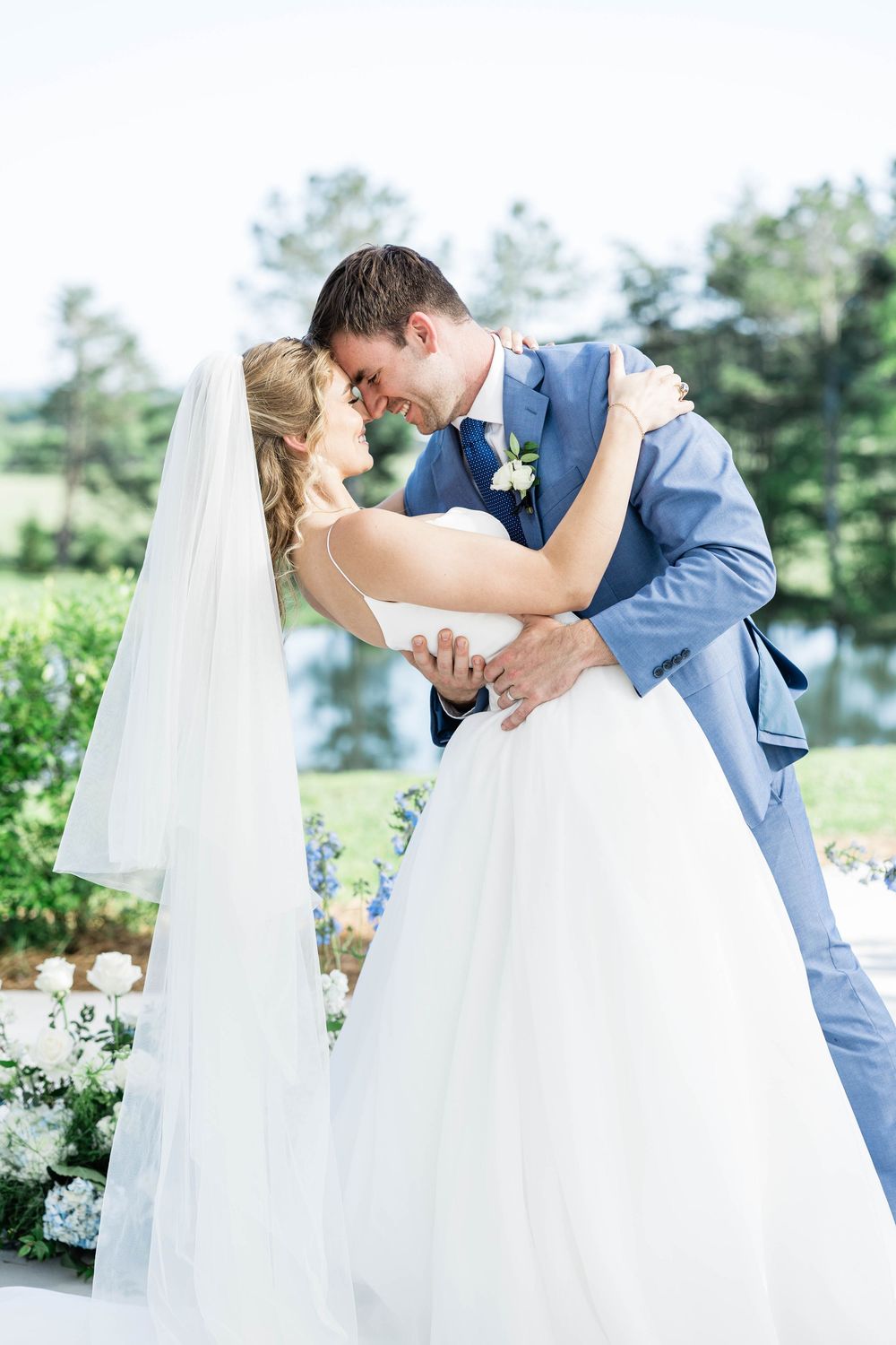 Romantic dip pose between newlyweds surrounded by elegant white flowers.