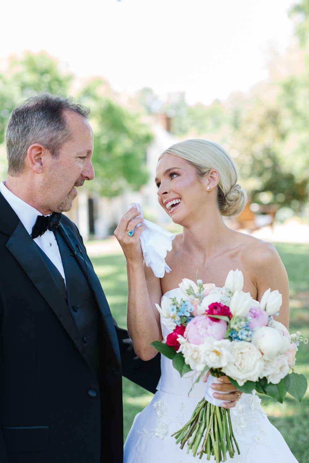 A heartfelt moment at an outdoor wedding with a beautiful bouquet of white and pink flowers.