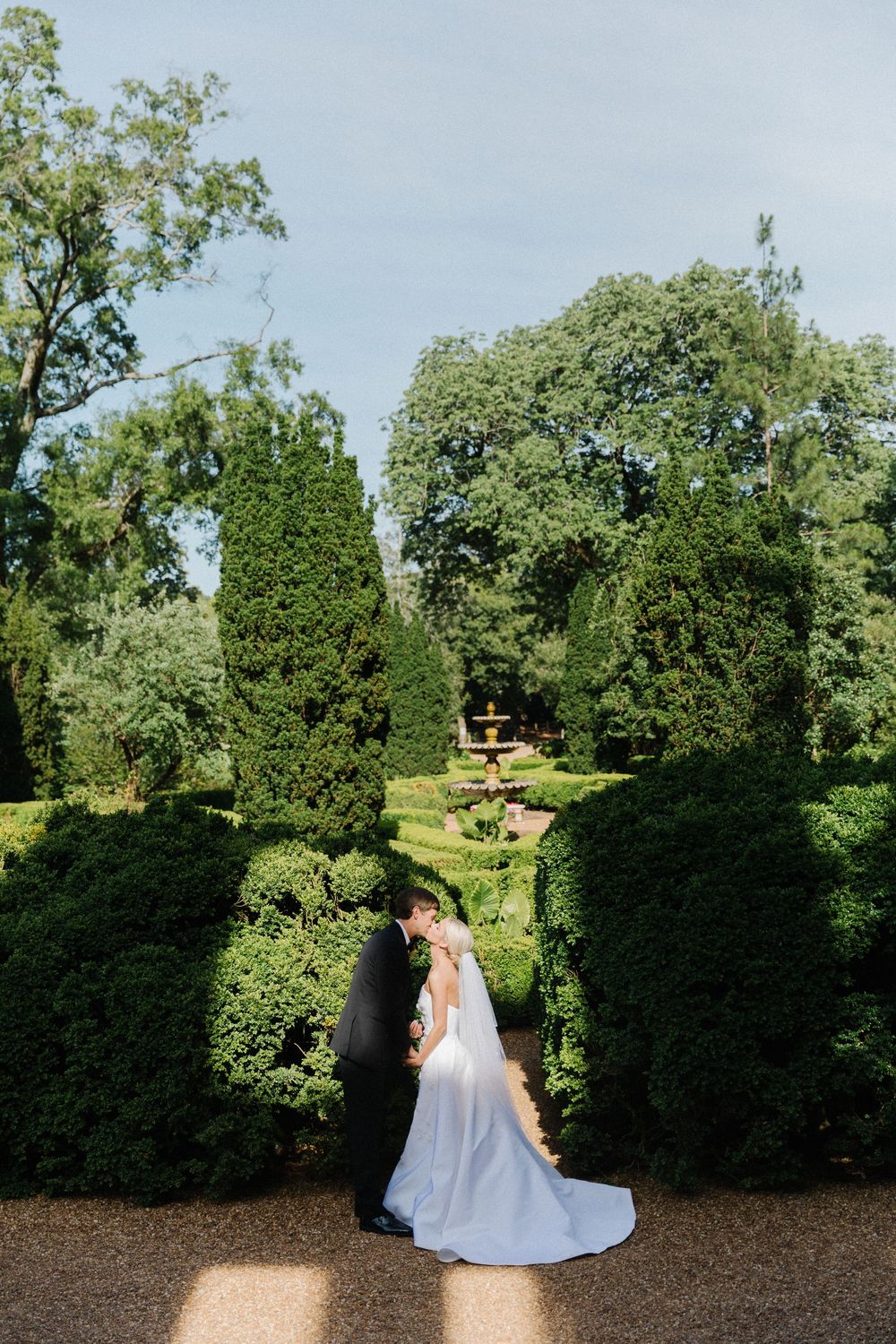 A tranquil garden path lined with tall manicured hedges creates an enchanting walkway surrounded by lush greenery.