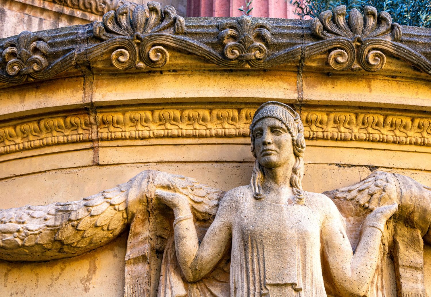 Ornate stone architectural carved figures decorating the San Francisco Palace Of Fine Art's exterior facade in golden sunlight.