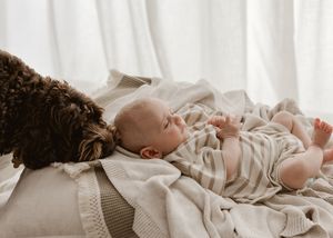 A sleeping baby lies peacefully in soft beige bedding while wearing a cozy knit sweater.