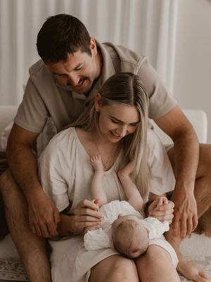 A series of intimate family moments showing parents bonding with their baby in a softly lit room.