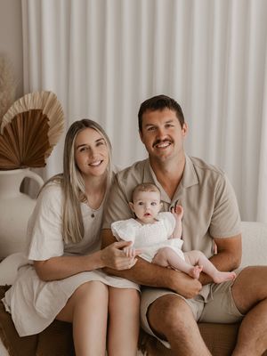 Family sitting together on a couch in neutral tones, sharing tender moments with their young child.