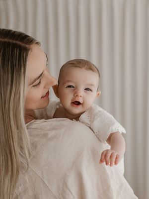 A tender moment between parent and baby in soft lighting against white curtains.
