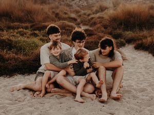 A group of cousins together on the sandy beach at sunset while sharing intimate conversations and laughter. Photographed on Papamoa beach