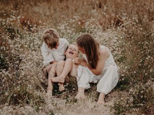 A candid moment of laughter and joy captured in a sunlit meadow with wildflowers.
