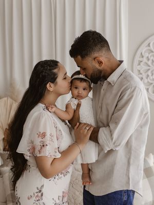 Family sharing tender moments together in white studio setting with soft lighting and floral dress details.