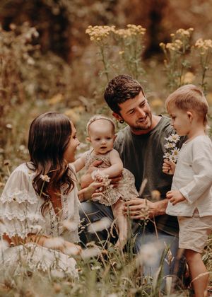 Family enjoying a tender moment together outdoors in a wildflower meadow on a warm autumn day. Photographed in a Forest