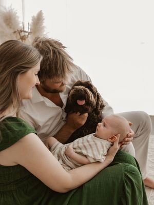 A family shares tender moments together while relaxing on a couch in neutral-toned clothing.