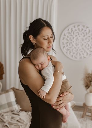 A tender moment captured in a series of photos showing a parent embracing and cuddling with their infant in a white room.
