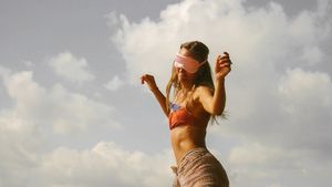 Silhouette dancing against cloudy sky in casual summer attire.