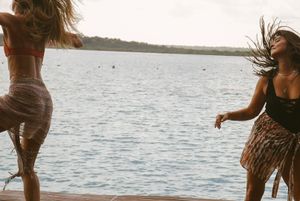 Two dancers moving expressively on dock against ocean backdrop.