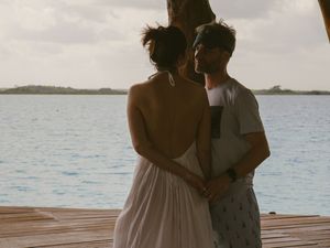 Couple embracing on oceanfront dock during sunset.