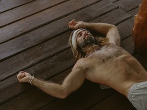 Person lying on wooden deck during outdoor relaxation session.