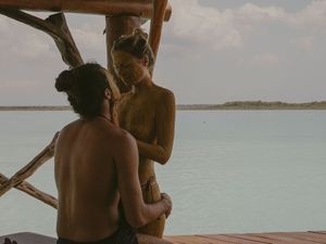 Intimate moment captured between couple on wooden deck over crystal waters.