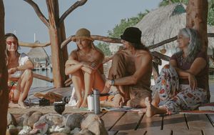 Group of friends relaxing on a covered wooden deck by the beach.