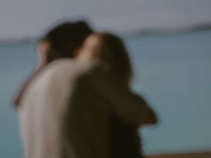 A soft focus intimate moment captured against a blurred blue background.