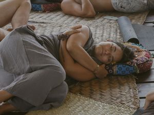 Person resting peacefully on patterned cushions and blankets.